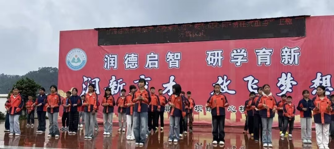 四川省凉山州甘洛县新市坝镇中心校关工委组织全校师生，以“国安记心间，责任共担当”为主题，在国旗下开展国家安全教育主题宣讲