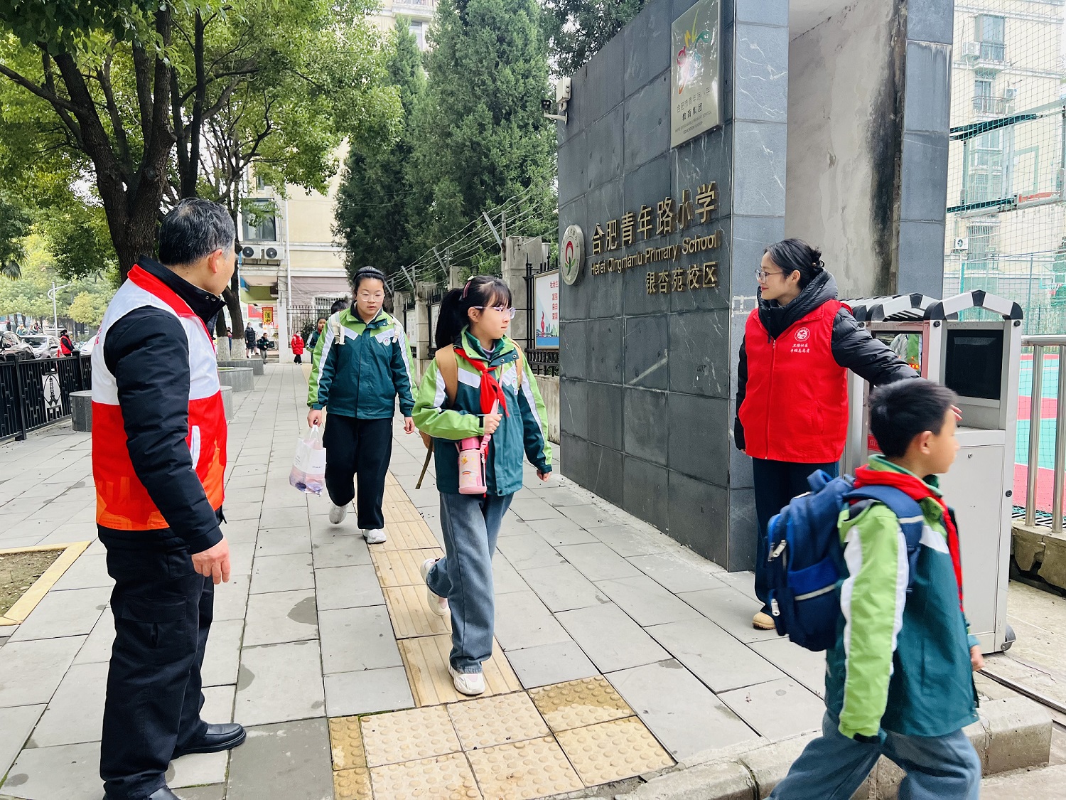 社区志愿者在校门口引导孩子们有序入校 1.jpg