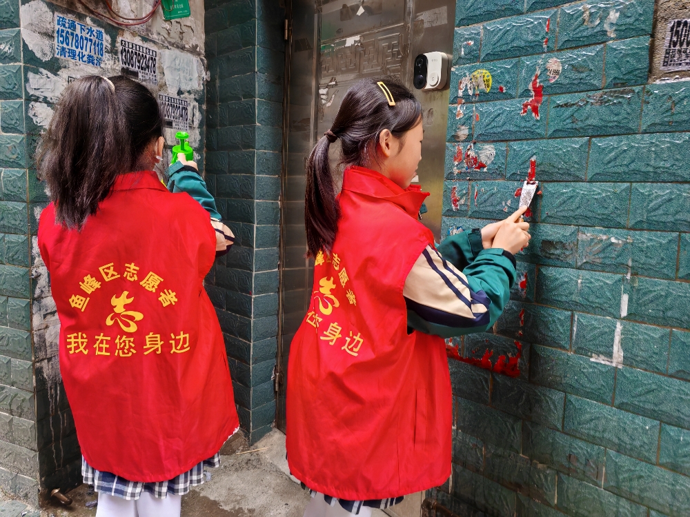 “红领巾”志愿者仔细铲除墙面上的“牛皮癣”小广告.jpg