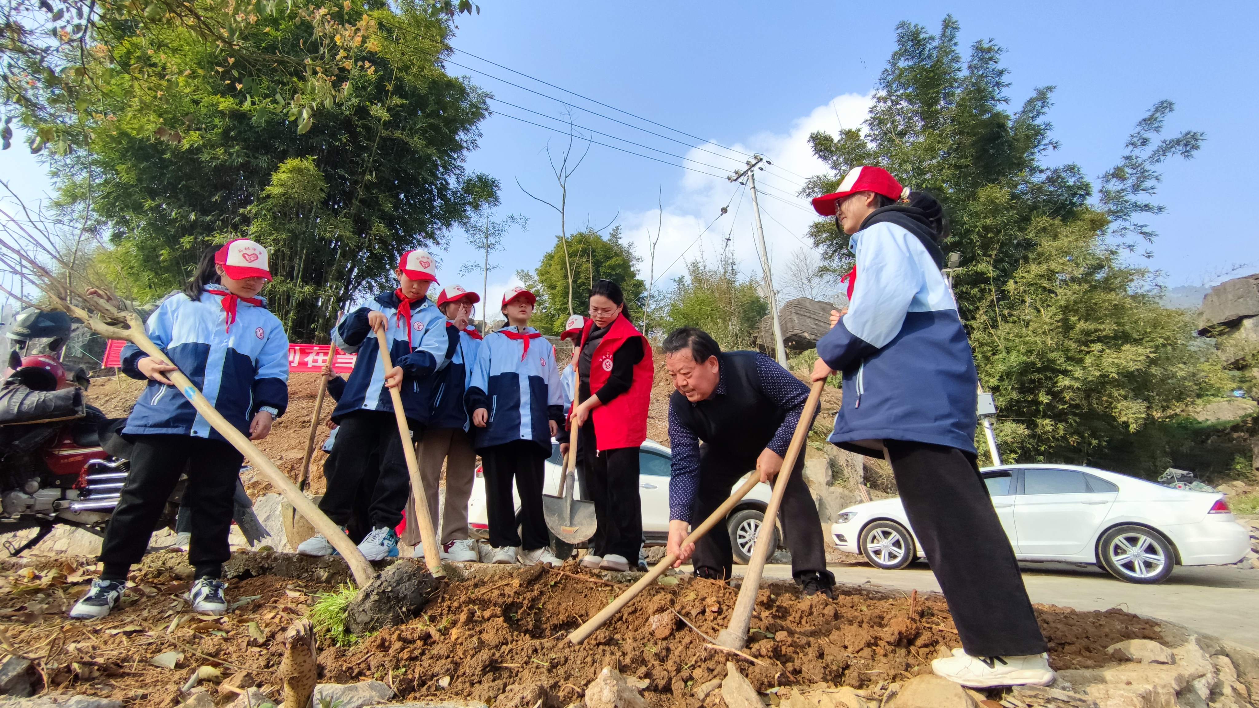 1710217673519768.jpg 3月11日,重庆市万盛经开区石林镇关工委、石林中学关工委联合开展“共建绿色生态,共享美丽家园”植树活动。镇关工委常务副主任曾庆财(右二)手把手指导孩子们栽种树木。1.jpg