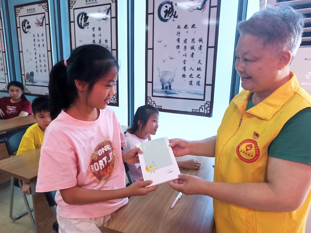“五老”志愿者给回答问题的小朋友送上笔记本1.jpg