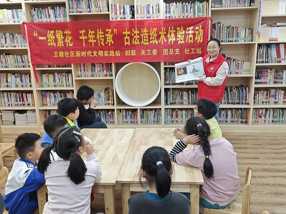 社区志愿者为孩子们讲述造纸术的历史和发展历程.jpg