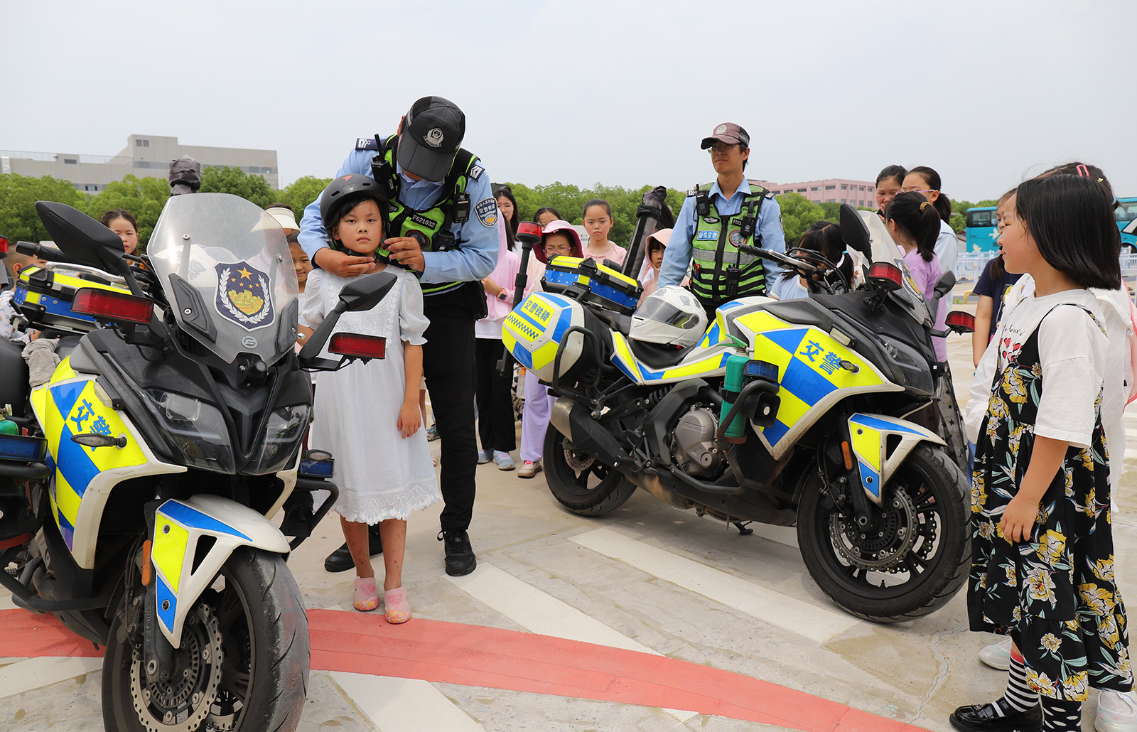 图为交警叔叔在手把手教工娃们正确佩戴头盔。02.JPG